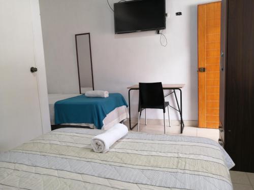 a room with two beds and a table and a television at Habitación en la playa in Tumbes