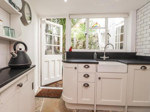 Tudor Cottage في ساندويتش: مطبخ بخزائن بيضاء ومغسلة ونافذة