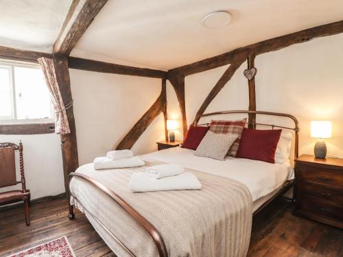 Tudor Cottage في ساندويتش: غرفة نوم بها سرير عليه منشفتان
