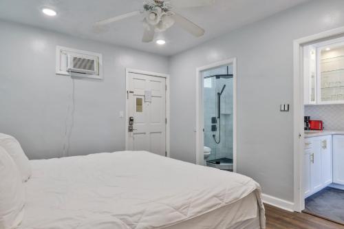 a white bedroom with a bed and a ceiling fan at Coastal Waters in New Smyrna Beach