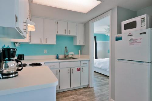 a kitchen with white cabinets and a white refrigerator at Coastal Waters in New Smyrna Beach