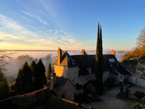 een oud huis op een heuvel met mist op de achtergrond bij Château de Nazelles Amboise in Nazelles