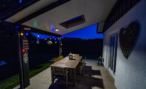 a table and chairs on a patio at night at Maison moderne à la campagne in Le Valdahon