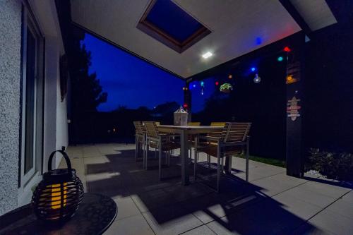 a table and chairs on a patio at night at Maison moderne à la campagne in Le Valdahon
