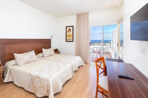 ein Hotelzimmer mit einem Bett, einem Schreibtisch und einem TV in der Unterkunft HC Hotel Magec in Puerto de la Cruz