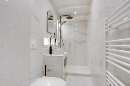 une salle de bain blanche avec une douche et un lavabo dans l'établissement Apartments in the heart of Paris in Sentier, à Paris
