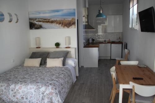 een slaapkamer met een bed en een tafel en een keuken bij Apartamento “CALMA” in Tarifa