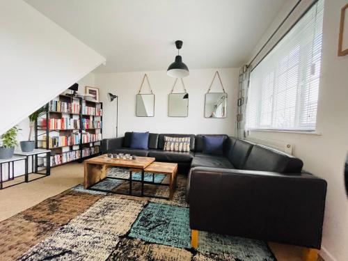a living room with a black couch and a coffee table at Cheerful 5-bedroom with free parking in Bristol