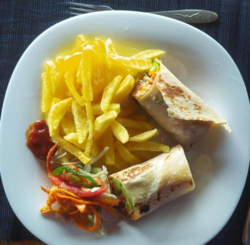 a plate of food with a sandwich and french fries at Mwamba Kelele Lodge in Fort Portal