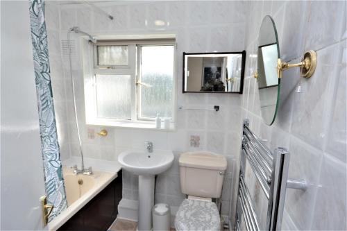 a white bathroom with a sink and a toilet at London Deluxe 3 Bedroom House with parking space in Dagenham