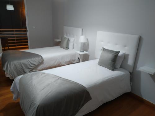 duas camas num quarto de hotel com lençóis e almofadas brancas em Sol & Mar Rancho em Câmara de Lobos