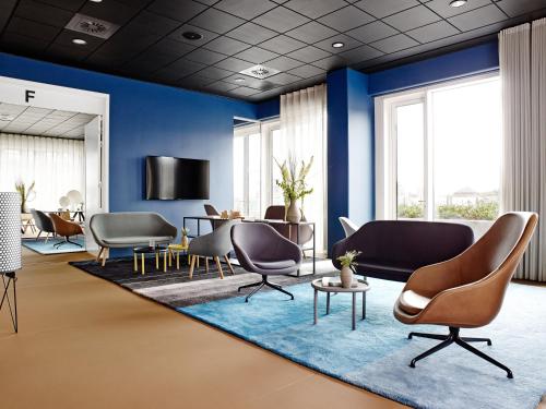a lobby with blue walls and chairs and tables at Comwell Aarhus Dolce by Wyndham in Aarhus