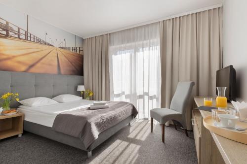 a bedroom with a bed and a desk and a television at Baltic Hotel in Gdynia