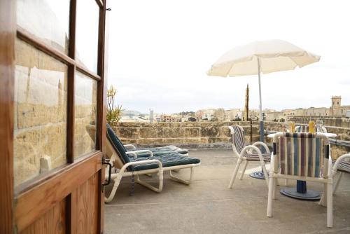 une terrasse avec des chaises, une table et un parasol dans l'établissement Gawhra B&B, à Victoria