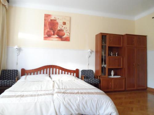 a bedroom with a bed and a wooden cabinet at Garden Szivárvány utcai Vendégház in Szeged