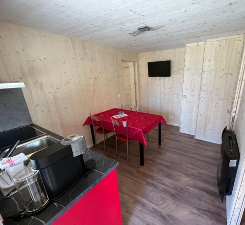 a room with a table with a red table cloth at Bungalow Miralago in Camping Cavresc, Via dal Cavresc 1, 7746 Le Prese-Poschiavo in Poschiavo