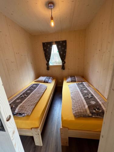 two beds in a cabin with a window at Bungalow Miralago in Camping Cavresc, Via dal Cavresc 1, 7746 Le Prese-Poschiavo in Poschiavo