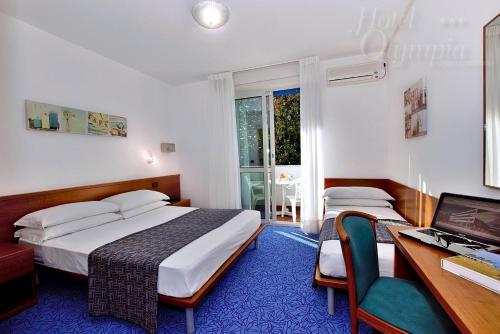 a bedroom with a bed and a desk and a computer at Hotel Olympia in Lignano Sabbiadoro