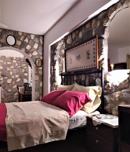 a bedroom with a large bed and a stone wall at Pasas Castle - Unique Luxury Apartments in Naxos Chora
