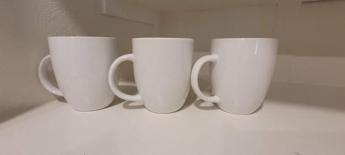 four white coffee cups sitting on a counter at Hotel Phillips in Bartlesville
