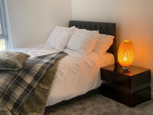 a bedroom with a bed with a lamp on a night stand at Lakeside 2 BED LUXURY APARTMENT No PARTIES No EVENTS Early Check-in Late Check- Out Allowed in West Thurrock