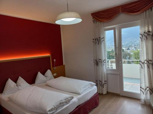 a bedroom with a bed and a large window at Hotel Lux in Merano