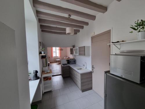 Il comprend une cuisine avec des murs blancs et des plafonds en bois. dans l'établissement Le murier ensoleillé, à Chinon