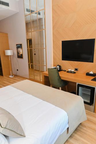 a bedroom with a bed and a desk with a television at White Hill Hotel, SPA & Conferences in Durrës