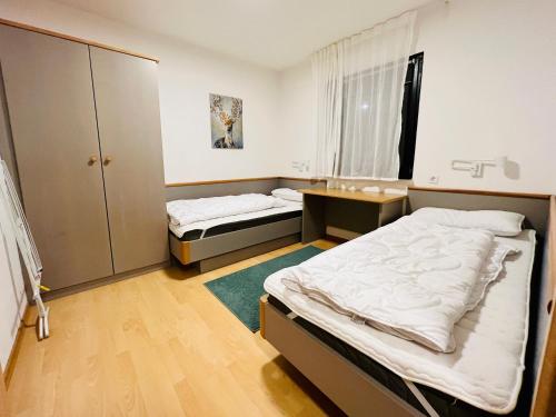 Habitación pequeña con 2 camas y escritorio. en Haus Lechbruck, en Lechbruck