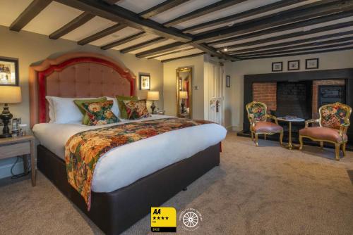1 dormitorio con 1 cama grande, mesa y sillas en The Tudor House Hotel, Tewkesbury, Gloucestershire en Tewkesbury