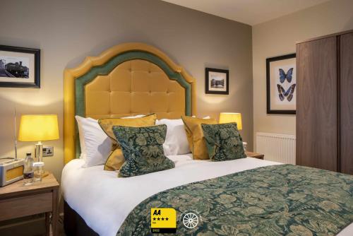 a bedroom with a large bed with pillows at The Tudor House Hotel, Tewkesbury, Gloucestershire - The Coaching Inn Group in Tewkesbury