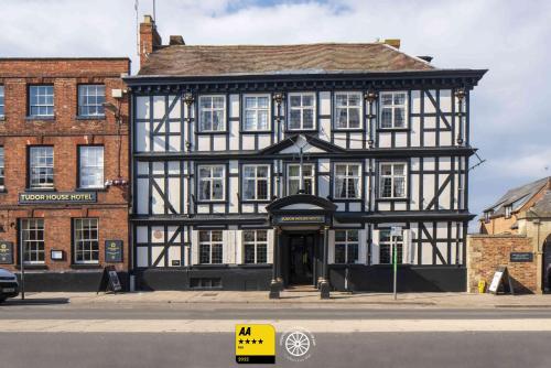 an old black and white building on a city street at The Tudor House Hotel, Tewkesbury, Gloucestershire - The Coaching Inn Group in Tewkesbury