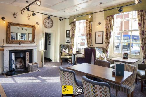 a room with a fireplace and a table and chairs at The Tudor House Hotel, Tewkesbury, Gloucestershire - The Coaching Inn Group in Tewkesbury