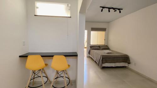 1 dormitorio con 1 cama y 2 sillas amarillas en Kalug - Apt Studio em Guest House na Praia do Sul, en Ilhéus