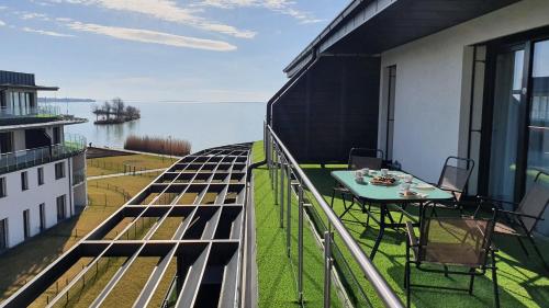 d'un balcon avec une table et des chaises et une vue sur l'eau. dans l'établissement Kékvitorla Apartman Keszthely, à Keszthely