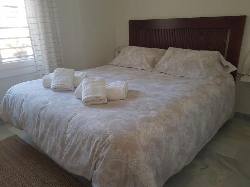 Apartamento "La Viña" في مالقة: سرير عليه شراشف بيضاء ومخدات بيضاء