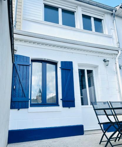 a house with blue shuttered windows and a chair at Escale 7 in Cayeux-sur-Mer