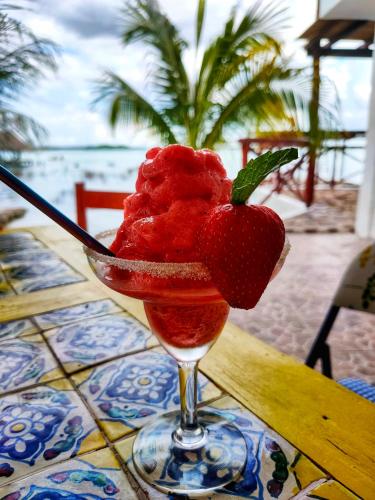 a drink with a strawberry in a glass on a table at El Búho Lagoon Bacalar in Bacalar