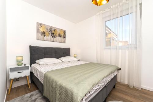 a white bedroom with a bed and a window at Blue waves, beachfront modern apartment in Mandre