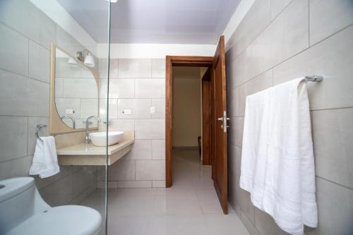 a bathroom with a toilet and a sink and a mirror at CoralK Apartments Sosúa in Sosúa