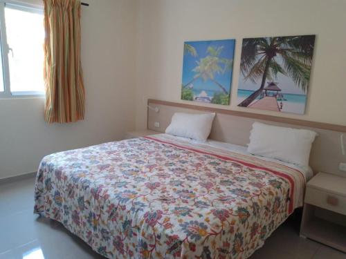 CoralK Apartments Sosúa في سوسْوا: غرفة نوم مع سرير مع لحاف جميل