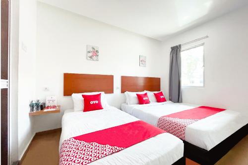 two beds in a room with red and white sheets at OYO 90334 Mawlaya Hotel in Bayan Lepas