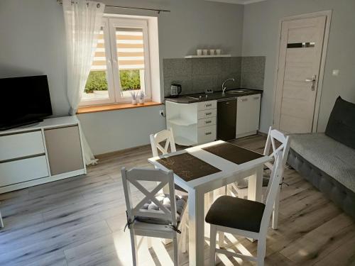 a kitchen and living room with a table and chairs at Apartamenty Konik Morski Ostrowo in Ostrowo