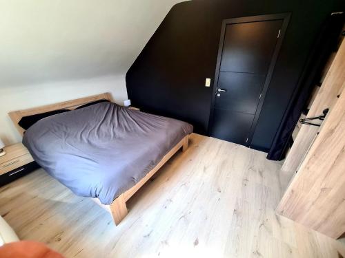 a small bedroom with a bed and a black door at Gîte au 14 - au calme avec jardin , proche de Dinant in Anhée