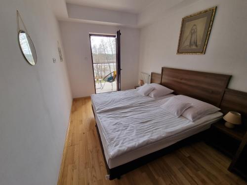 a bedroom with a large bed with white sheets and a window at Apartament Perła A20 nad jeziorem Pluszne in Olsztynek
