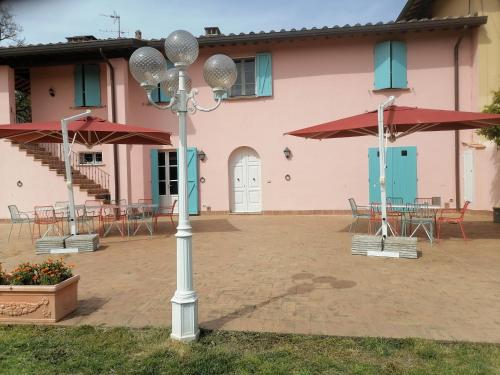 a light pole in front of a building with tables and umbrellas at Az.Agricola Agriturismo La Locanda di LANN in Fucecchio
