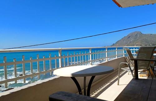 a balcony with a table and chairs and the ocean at En Plo Studios & Apartments in Plakias