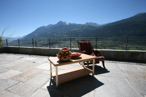 a table with a bowl of fruit and a chair at Bellevue in Aosta