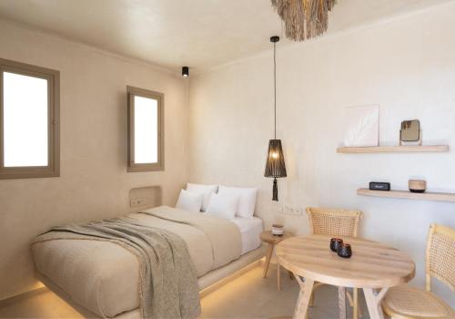 a bedroom with a bed and a table and two windows at Areos Luxury Suites in Vóthon
