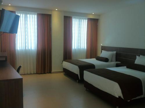 a hotel room with two beds and curtains at Hausen Hotel - Suites in Montería